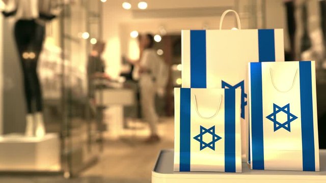 Flag of Israel on the paper shopping bags against blurred store entrance. Retail related clip
