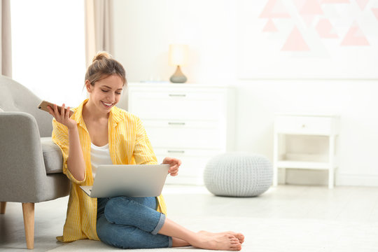 Young woman with smartphone using laptop at home