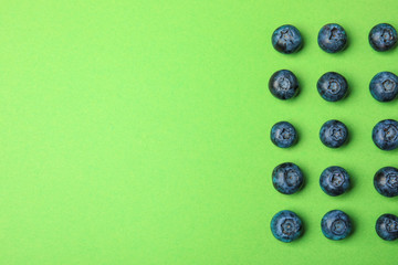 Tasty ripe blueberries on green background, flat lay with space for text