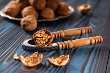 Vintage walnut cracker and walnuts on a blue wooden background.