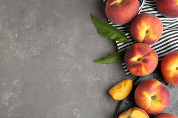 Fresh tasty peaches, fabric and leaves on grey stone surface, top view with space for text