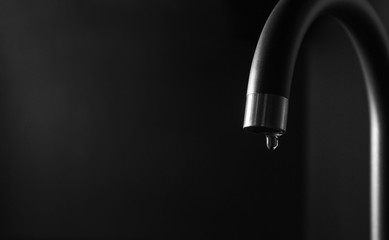 Closeup view of water dropping from faucet indoors. Space for text