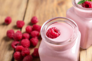 Glass jar of tasty smoothie with raspberries on wooden table, closeup. Space for text