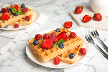 Delicious waffles with fresh berries served on white marble table