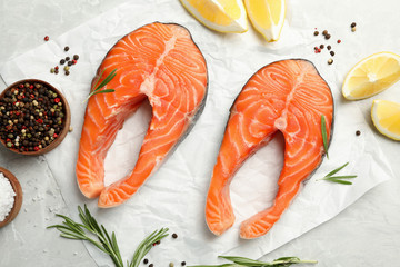 Fresh salmon steaks with spices, lemon and rosemary on marble table, flat lay