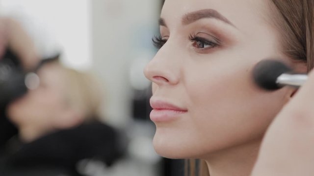 Professional makeup artist woman stirs makeup cream on a palette.
