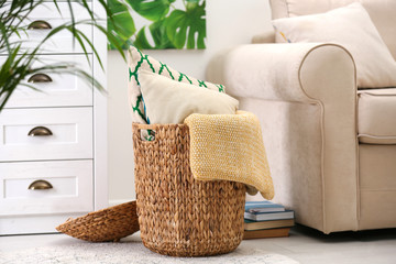 Basket with soft plaid and pillows in living room interior