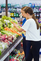 Teen girls shopping in supermarket reading product information. Choosing daily product.Concept of healthy food, bio, vegetarian, diet.