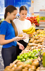 Obraz premium Teen girls shopping in supermarket reading product information. Choosing daily product.Concept of healthy food, bio, vegetarian, diet.