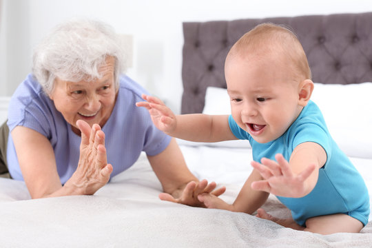 Cute little baby with happy grandmother in bedroom