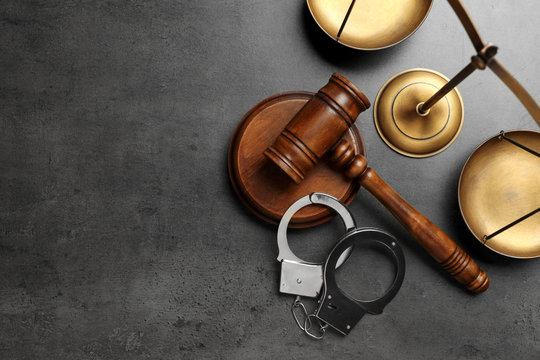 Judge's gavel, handcuffs and scales on grey background, flat lay with space for text. Criminal law concept