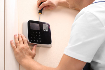 Male technician installing security alarm system indoors, closeup
