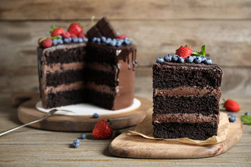 Delicious chocolate cake decorated with fresh berries on wooden table