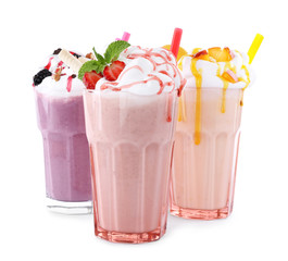 Different tasty milk shakes in glasses on white background