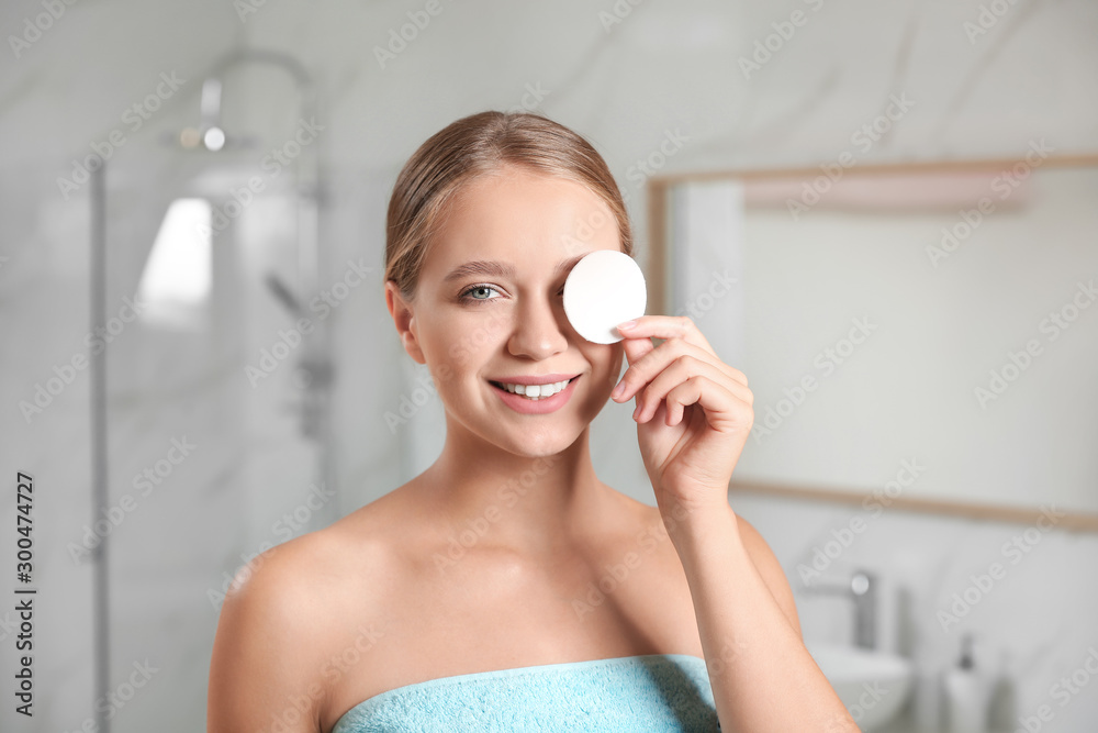 Wall mural Beautiful young woman with cotton pad indoors