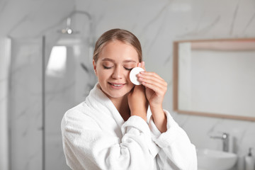 Beautiful young woman with cotton pad indoors