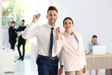 Happy young employees with darts in office