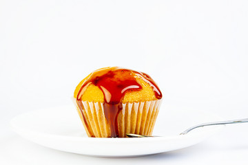 HONEY COVERED MUFFIN ON PLATE AND METAL SPOON ON WHITE BACKGROUND