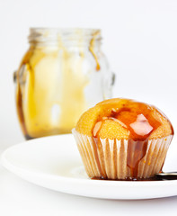 MUFFIN WITH HONEY AND CRYSTAL JAR WITH HONEY AND SPOON ON WHITE BACKGROUND