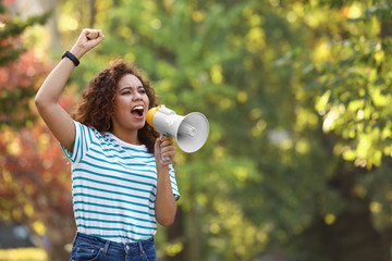 Angry African-American woman with megaphone outdoors. Protest leader
