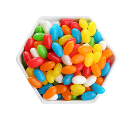 Bowl of tasty jelly beans on white background, top view