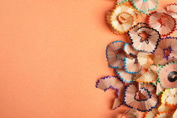 Pencil shavings on orange background, top view. Space for text