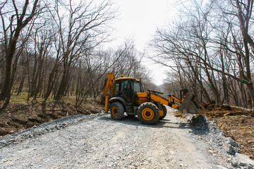 Road construction machinery stands on a dirt road. The construction of a new road in the suburbs.