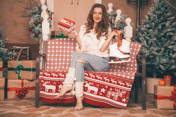 charming thin girl in fashionable jeans embroidered with pearls and Christmas sweater barefoot sitting on a bench, full length body