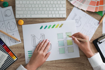 Female designer working at wooden table, top view