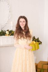 beautiful slim caucasian adult woman in long evening yellow dress holding gift box with bow and...