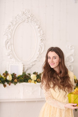 beautiful slim caucasian adult woman in long evening yellow dress holding gift box with bow and...