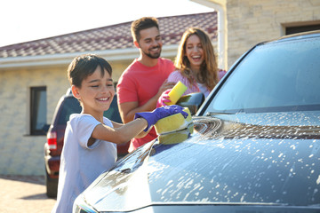 Happy family washing car at backyard on sunny day