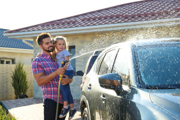 Dad and daughter washing car at backyard on sunny day - Powered by Adobe