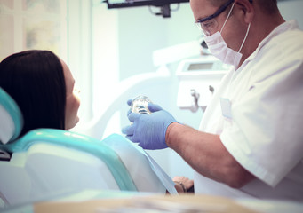 Image of young lady with dentist over her before checking oral cavity