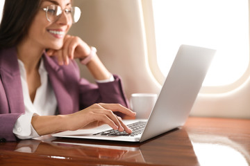 Young woman working with laptop on plane, closeup