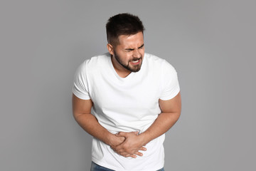 Man suffering from abdominal pain on light grey background