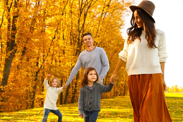 Fototapeta premium Happy family with little daughters walking in autumn park