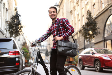Fototapeta na wymiar Handsome happy man with bicycle on city street