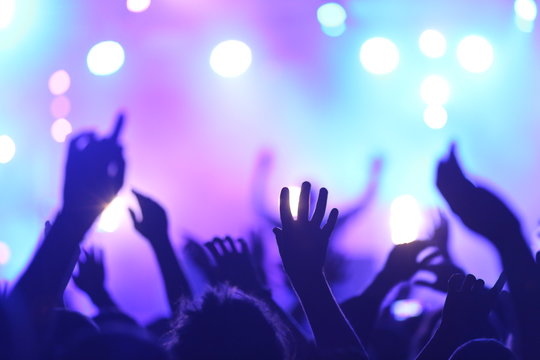 Background Music and Events.  Mains agit&eacute;es, la foule danse avec la musique, &eacute;clairage violet et bleu. Ambiance de f&ecirc;te durant un Festival et Concert de Musique.