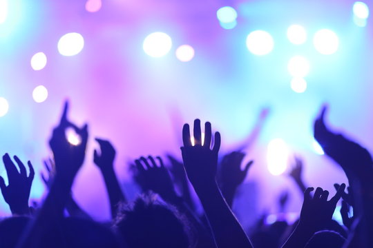 Background Music and Events. Ambiance de f&ecirc;te durant un Festival et Concert de Musique. Mains agit&eacute;es, la foule danse avec la musique, &eacute;clairage bleu et violet.