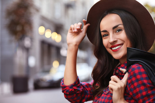 Beautiful woman wearing hat in city on autumn day