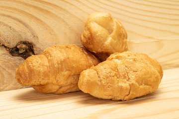 Group of three whole fresh baked mini croissant on natural wood