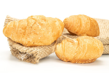 Group of three whole fresh baked mini croissant with jute bag isolated on white background