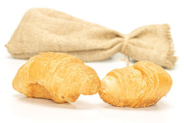 Group of two whole fresh baked mini croissant with jute bag isolated on white background