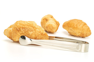 Group of three whole fresh baked mini croissant with sugar tongs isolated on white background