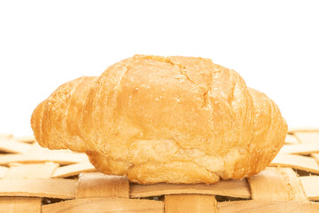 One whole fresh baked mini croissant on bast basket isolated on white background