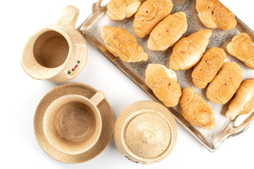 Lot of whole fresh baked mini croissant on tray with cup , sugar bowl and ceramic jug flatlay isolated on white background