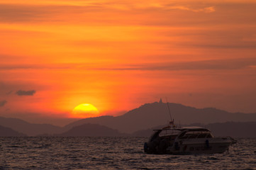 Fototapeta na wymiar sunset on the sea with boat and mountain