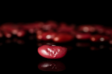 Lot of whole fresh red kidney beans isolated on black glass