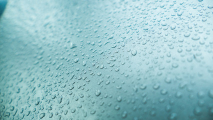 Water drops from the rain on the glass with blue tones